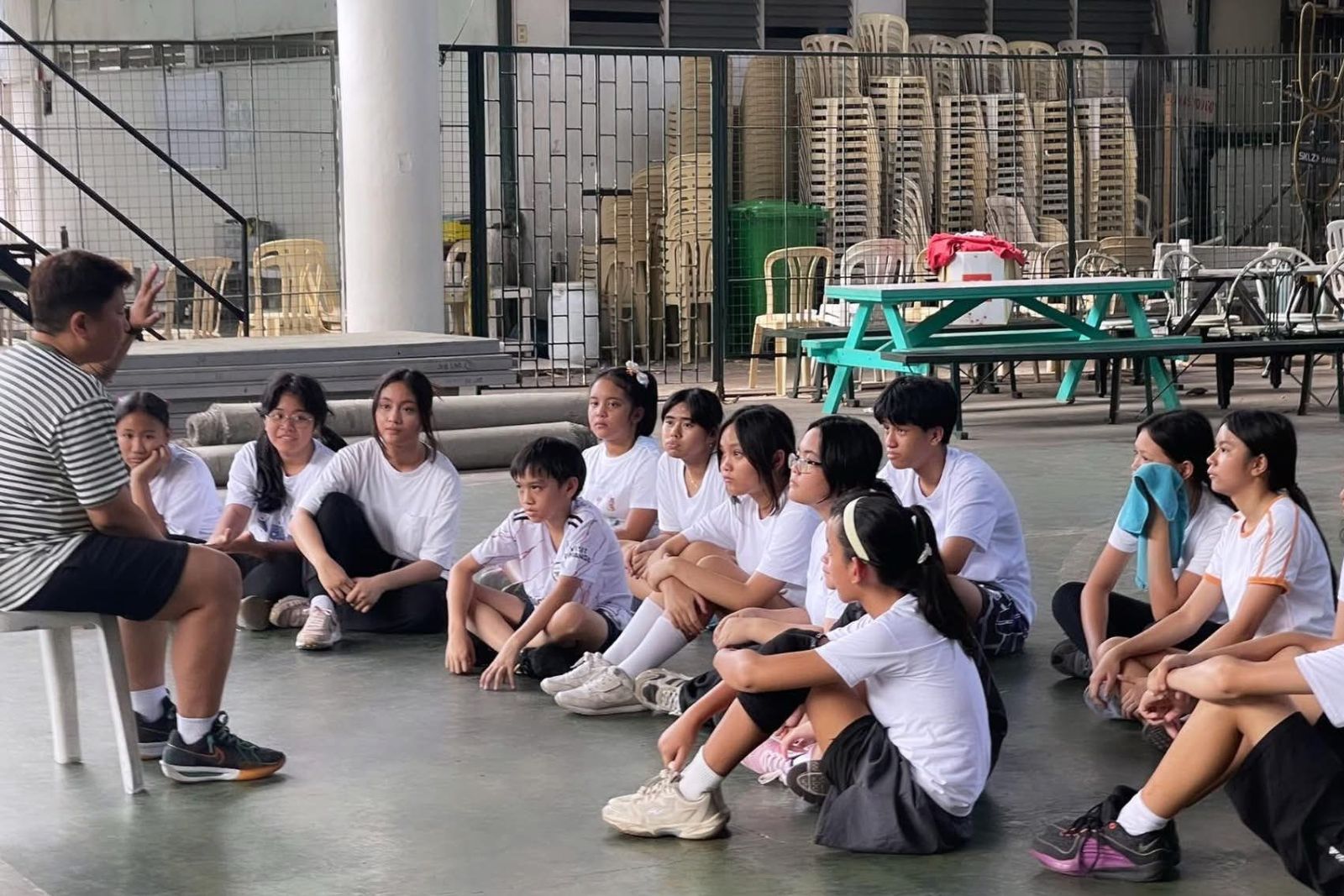 Coach Larmy briefing a group of seated athletes before a training session